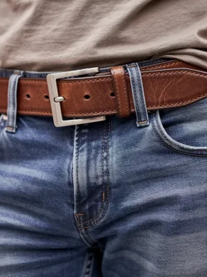 Close-up of a classic brown leather belt worn with denim, highlighting texture and buckle detail for casual style.