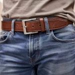 Close-up of a classic brown leather belt worn with denim, highlighting texture and buckle detail for casual style.