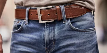 Close-up of a classic brown leather belt worn with denim, highlighting texture and buckle detail for casual style.