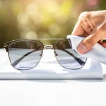 Hand cleaning sunglass lenses with microfiber cloth